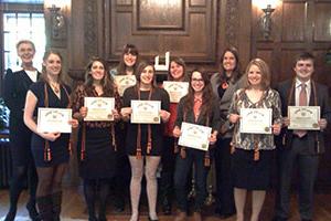 Group photo of students holding certificates and two professors